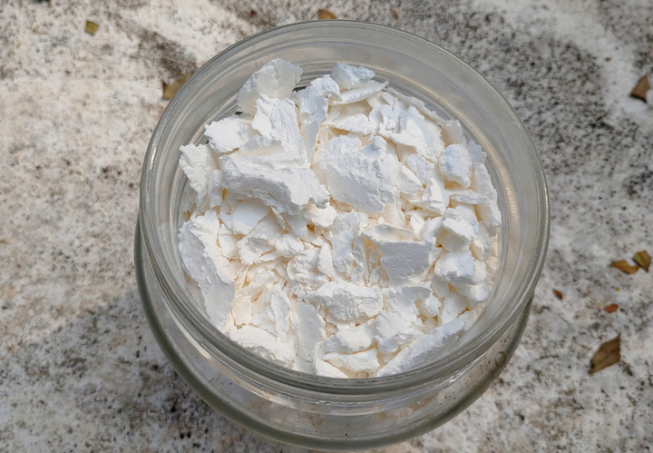 A glass jar filled with white flakes on a textured surface.