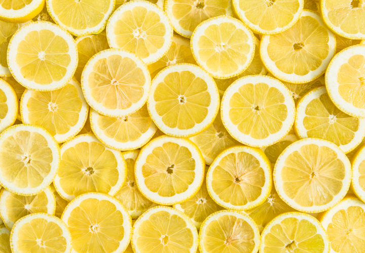 Slices of fresh yellow lemons are arranged closely together.