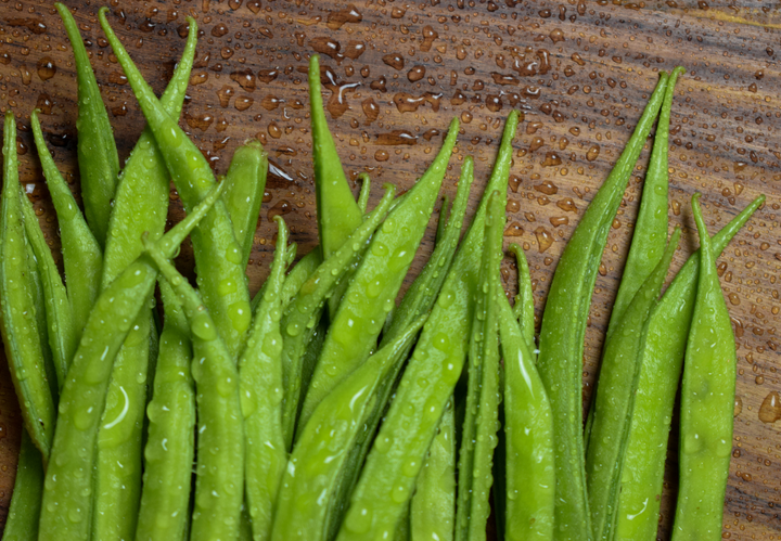 Fresh green beans on a wet wooden surface.